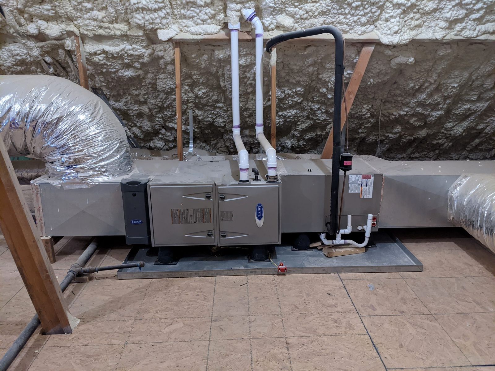 Carrier Infinity gas furnace and coil installed horizontally in a spray-foamed attic, mounted on isolation pads with sealed sheet metal plenums